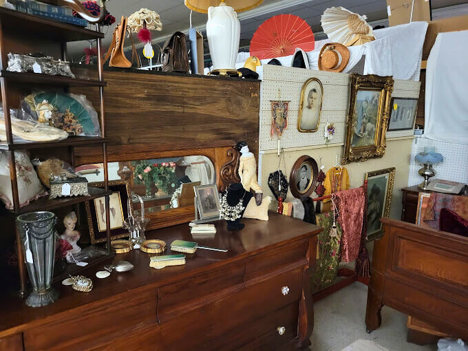 Vintage vanity with antique collectibles, wall art, and hats on display at Elmwood Antique Centre in Abilene, TX