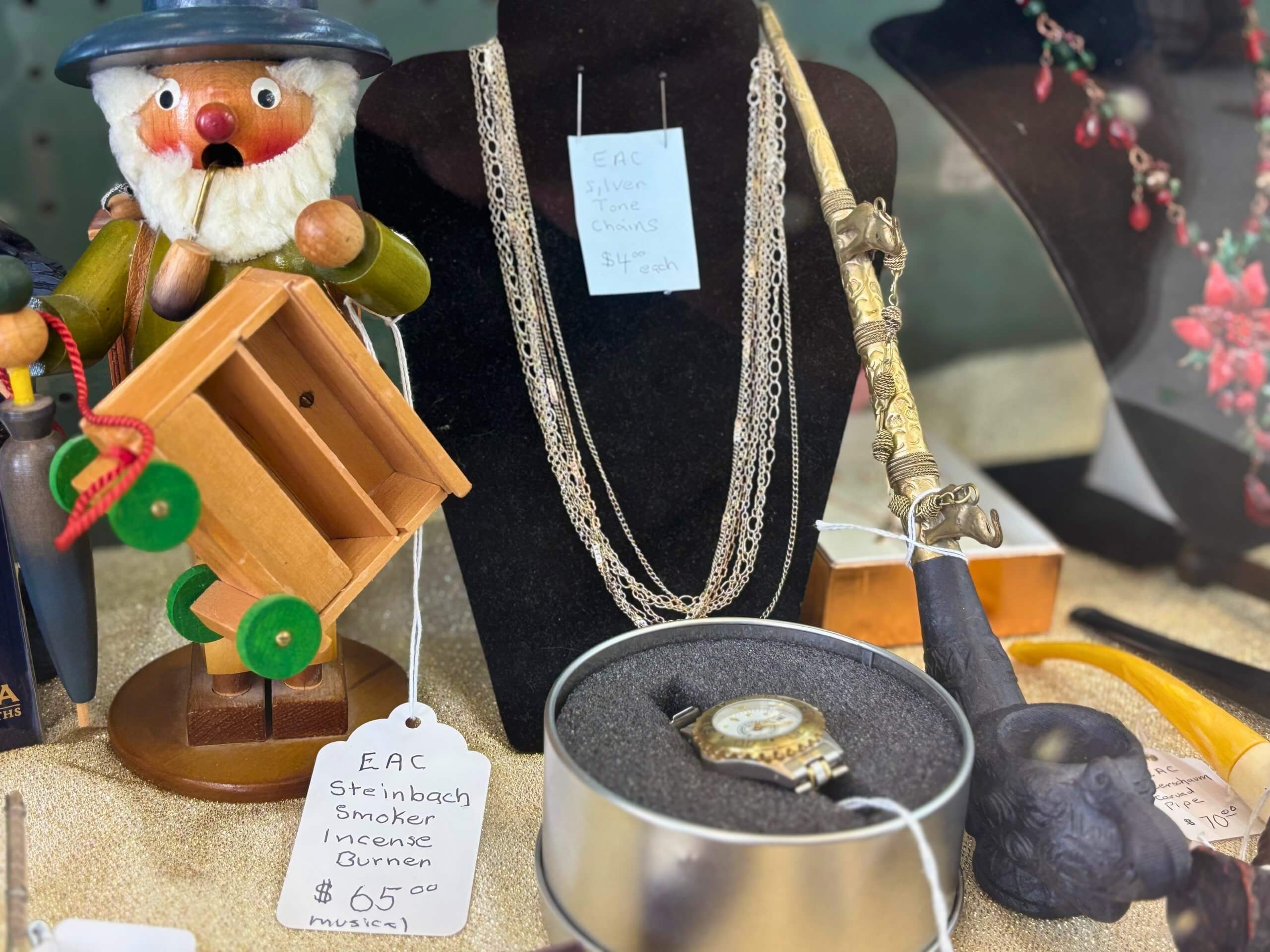 Display of vintage items including a Steinbach Smoker incense burner, silver-tone chains, and a collectible watch at Elmwood Antique Centre in Abilene, TX